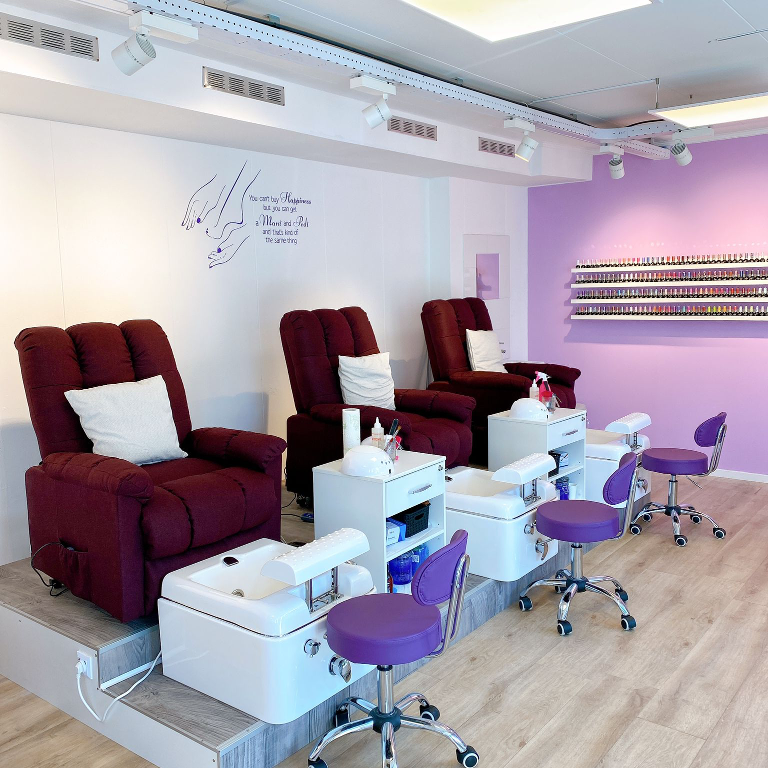 De salon: drie bordeauxrode pedicurestoelen met witte voetbaden voor de lila wand met lakjes